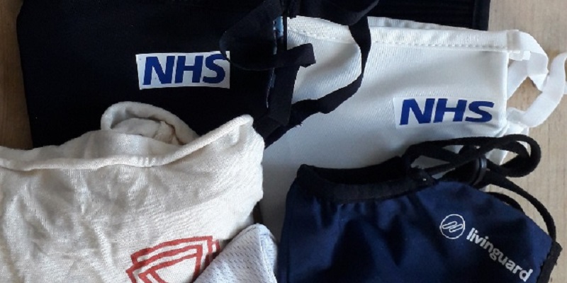 a number of reusable masks in different colours with the NHS logo on