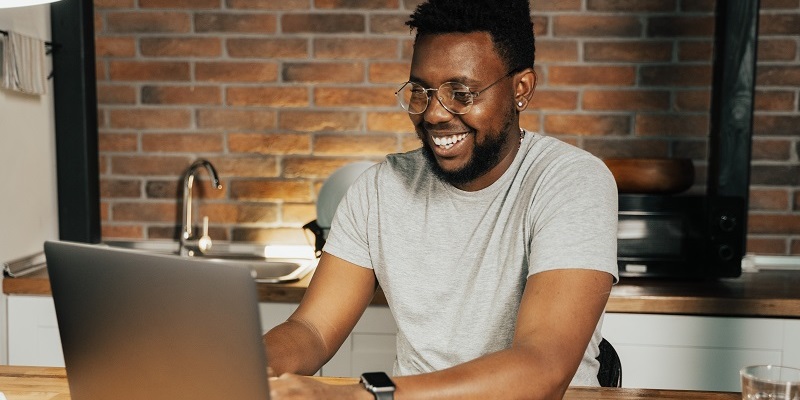 man at a table with laptop smiling