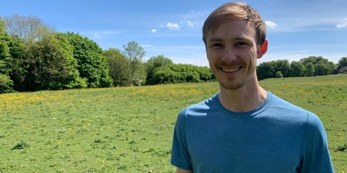 Man facing camera smiling with field behind them