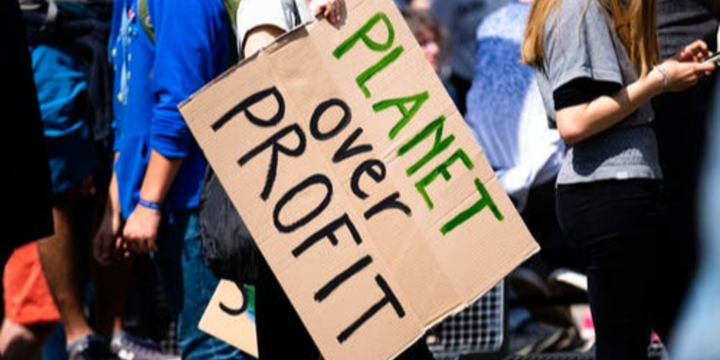 Cardboard sign reading planet over profit