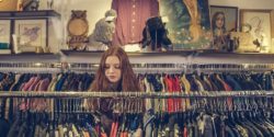 A lady with ginger hair looking through the clothes rails at a charity shop