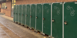 A row of green enclosed bike shelters