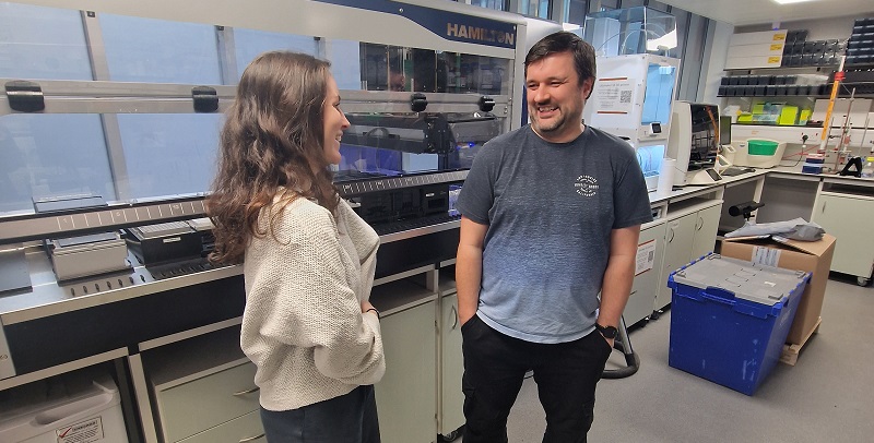 Photo of two people stood chatting in the lab