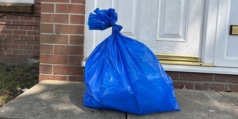 A blue bin bag full of donations on a doorstep