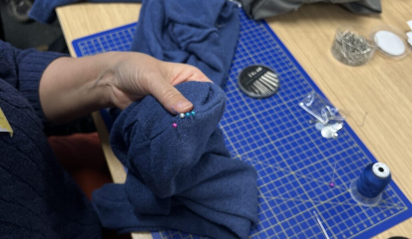 Hands sewing a blue fabric
