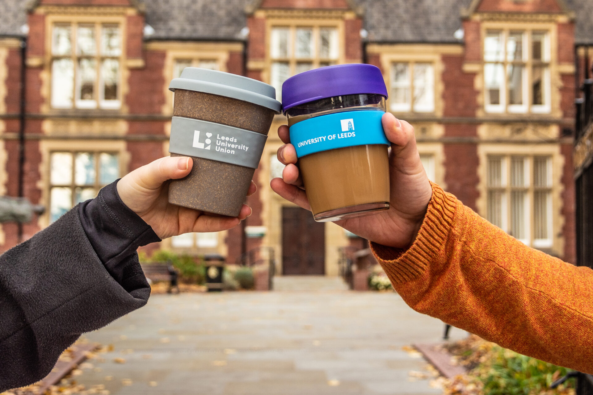 Two university, reusable 'keep cups' being held up