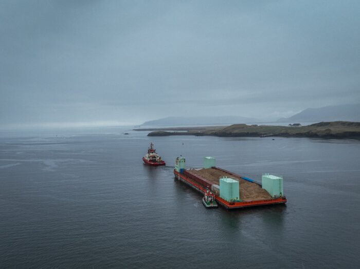 A ship at sea off the coast of Iceland towing a barge.