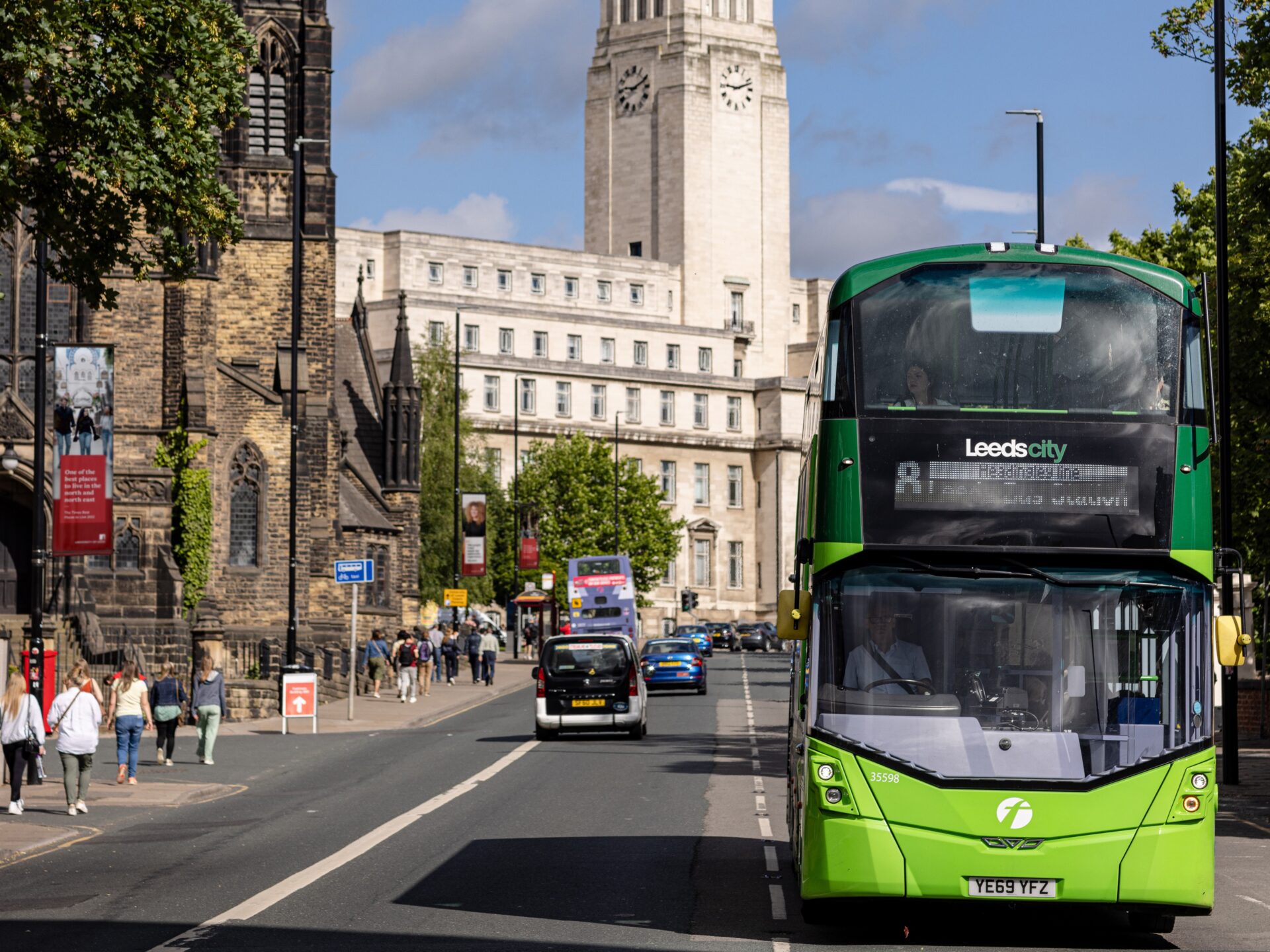 A green bus driving down Blenheim Terrace with the white Parkinson Building in the background.