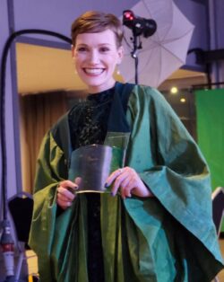 Hazel Mooney holds her award while wearing the green gown. She is smiling