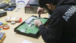 A student, equipped with a screwdriver, fixes a circuit board.