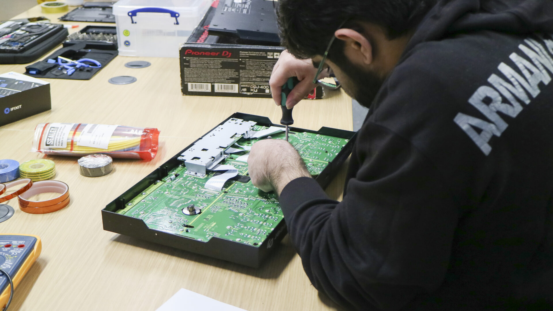 A student using tools to fix an electronic item