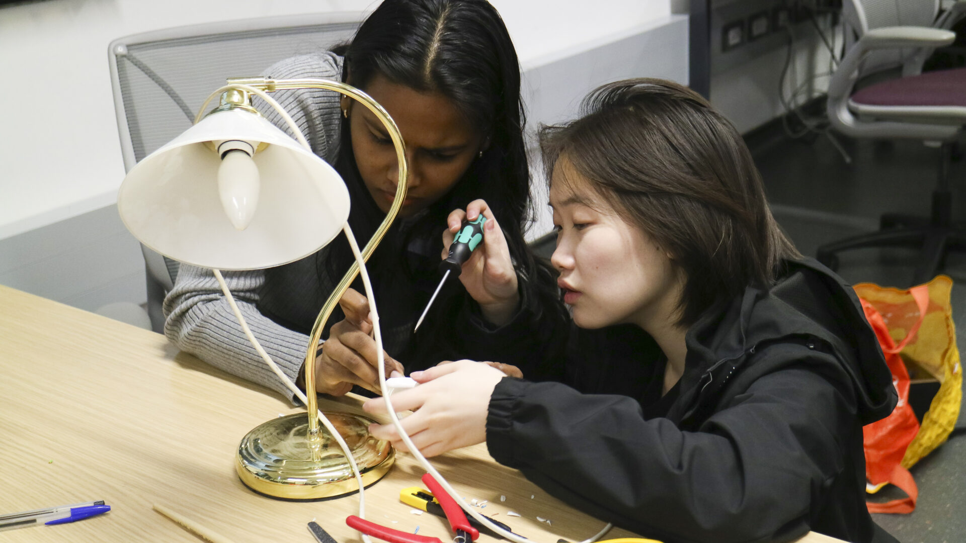 Two female-presenting students fixing a lamp