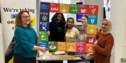 Group of women holding a photo frame, which has the 17 United Nations Sustainable Development Goals (SDGs) written around the edges of the frame