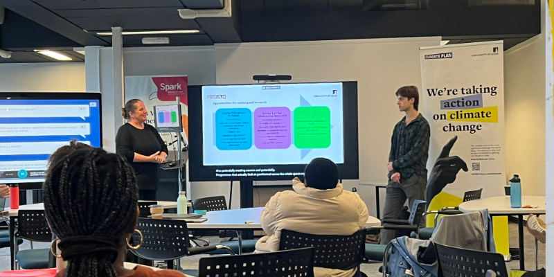 A seminar with two people at the front presenting from a screen.