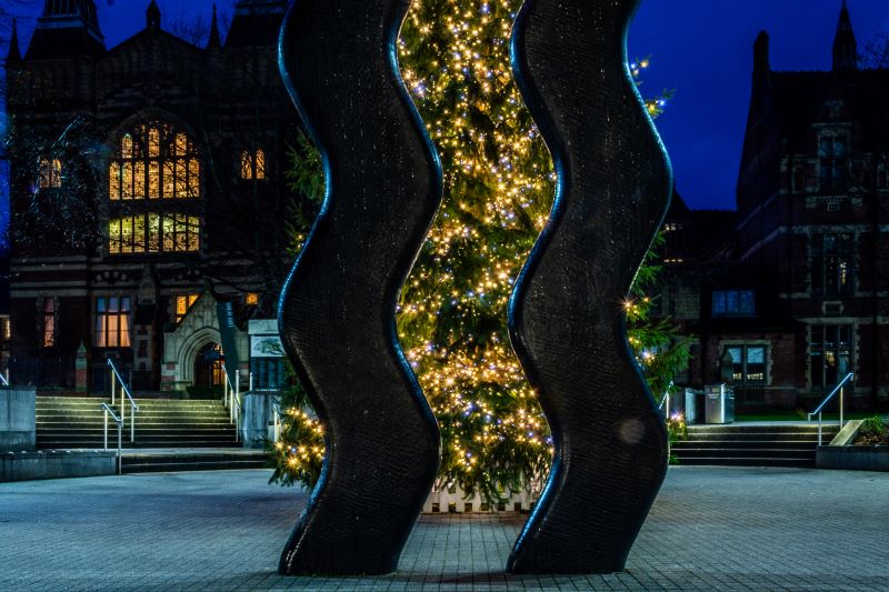 The sign of art is in the foreground with the campus Christmas Tree lit up in the background