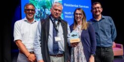 Staff members hold an award in front of a crowd