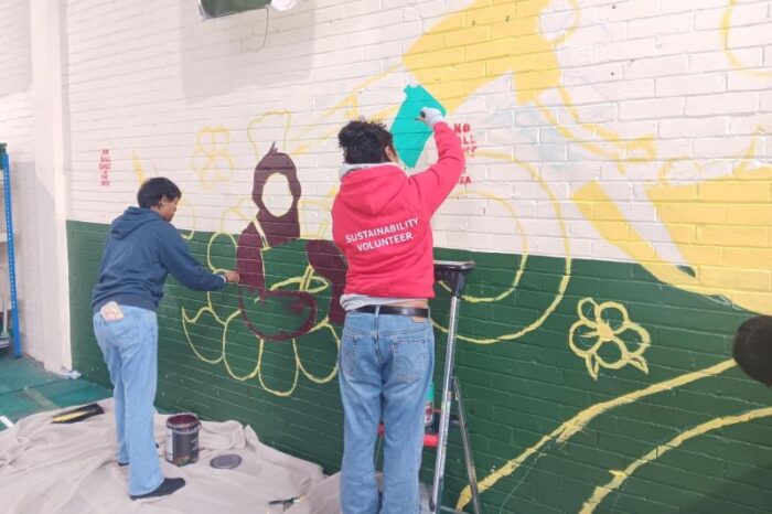 Two student volunteers painting the mural 