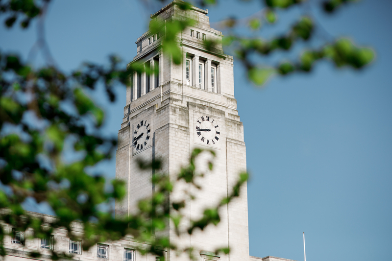 Parkinson Building, partially covered by tree branches with a blue sky in the backdrop.