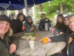 A group of volunteers sat around a wooden table in the Sustainable Garden.
